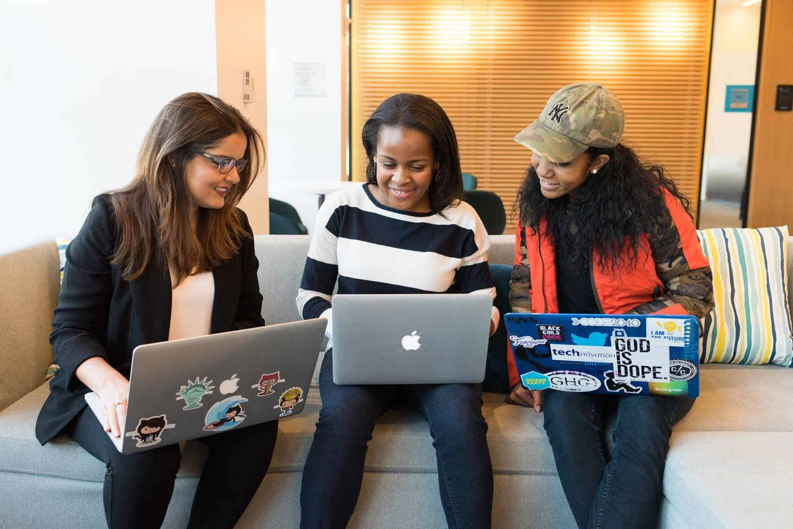 Three digital professionals collaborating on laptops in an office.