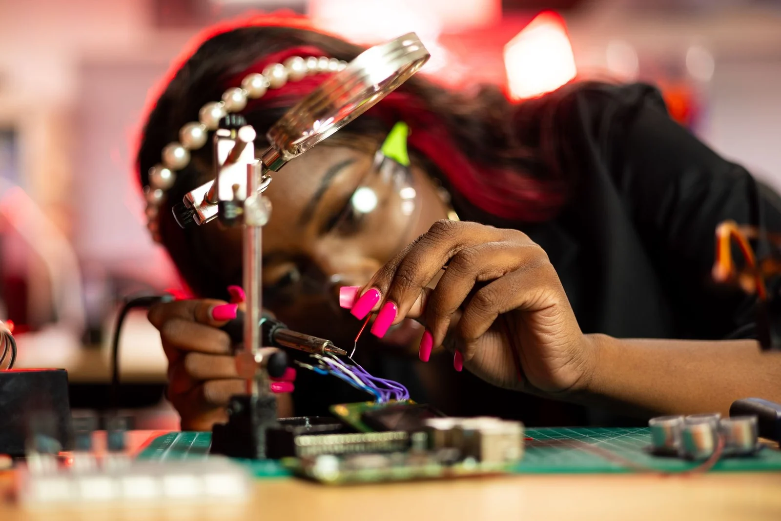 An engineer carefully assembling electronic hardware under a magnifying lamp.
